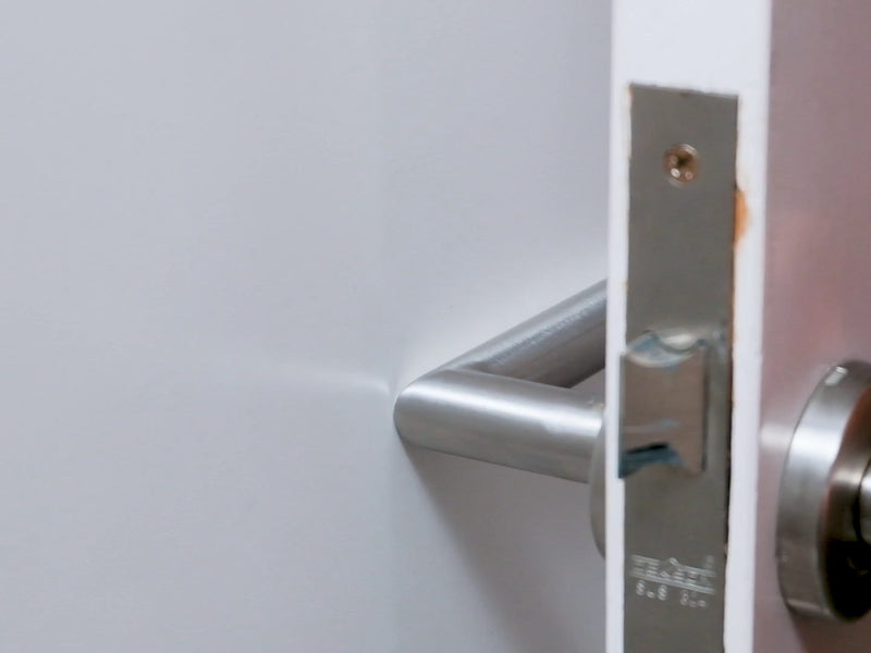 Lever handle touching the bare wall, marking the spot